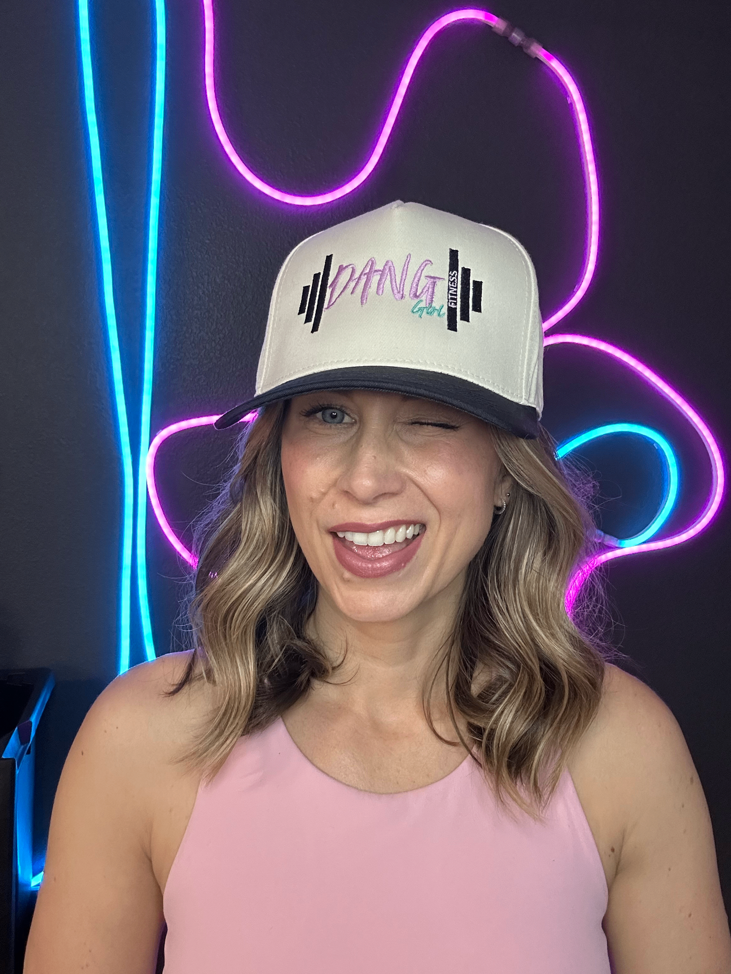 Leslie winking in a Dang Girl Fitness hat